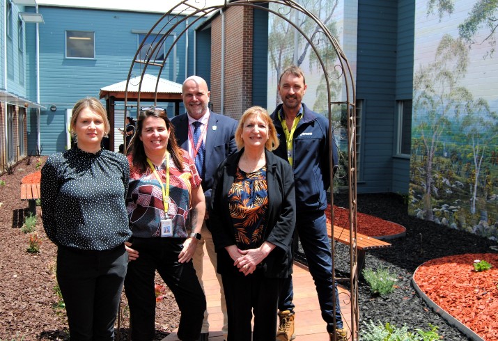 Staff and community members stand at entrance to new community wellbeing garden