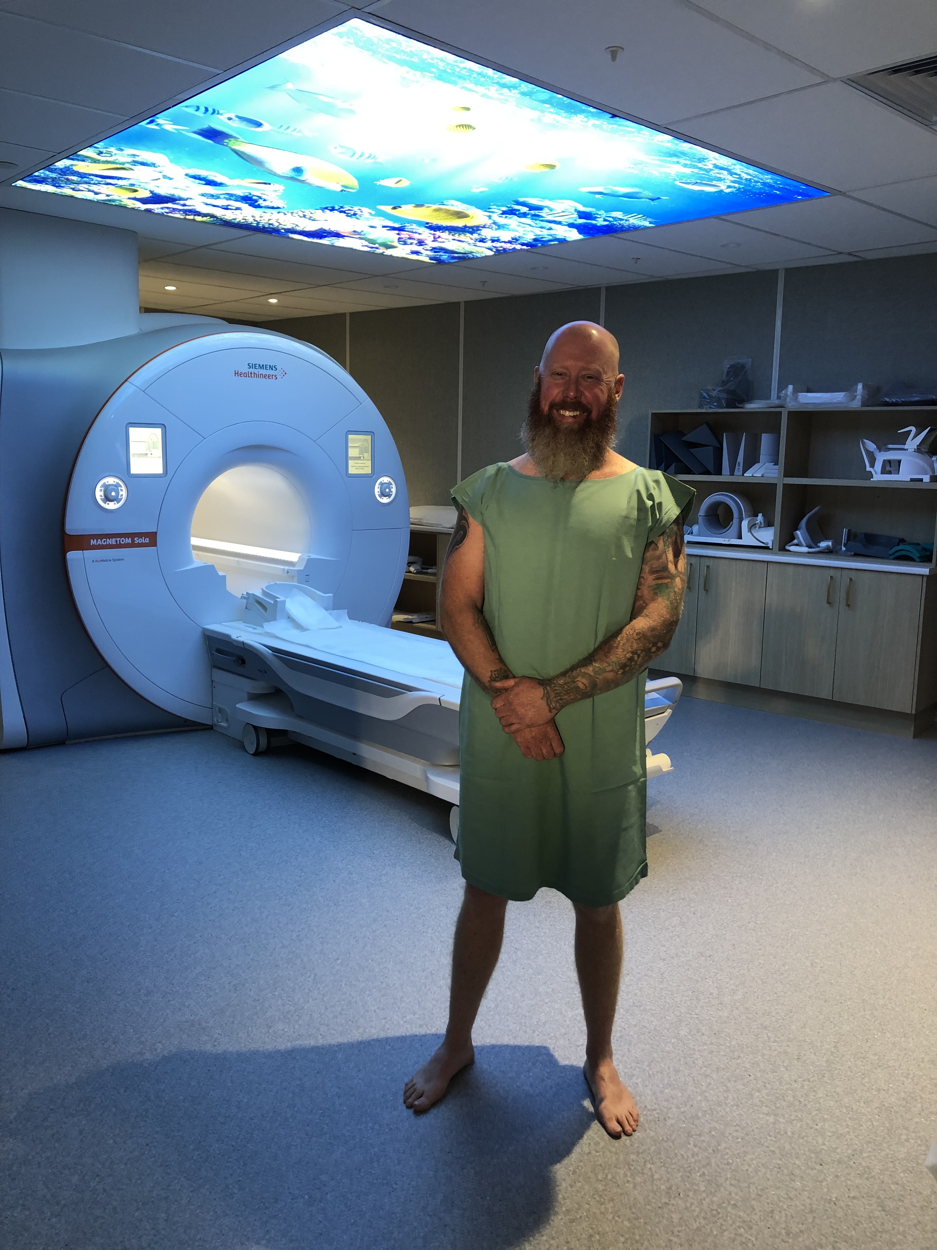 First patient smiles in gown in front of MRI