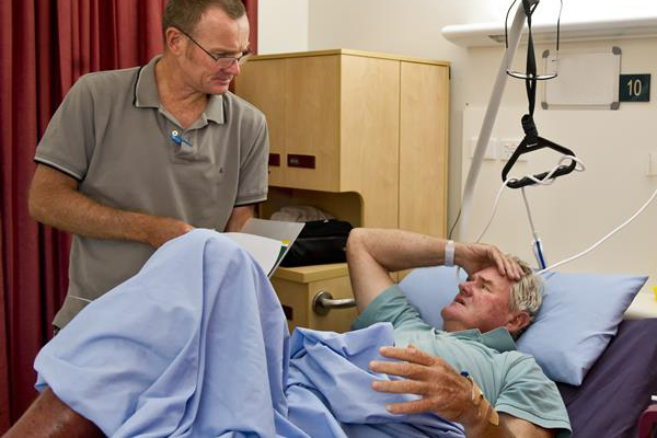 Doctor discusses chart with elderly male patient