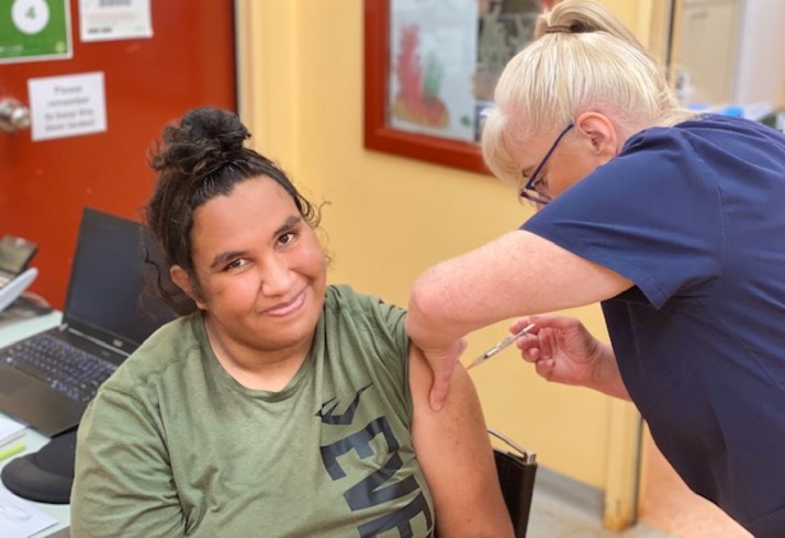 Young woman receives COVID-19 vaccine from nurse 
