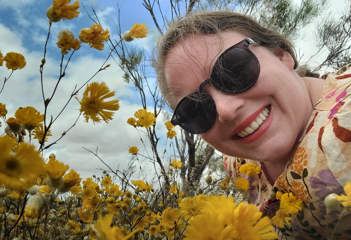 Dr Kelly Ridley in a field of yellow wildflowers 