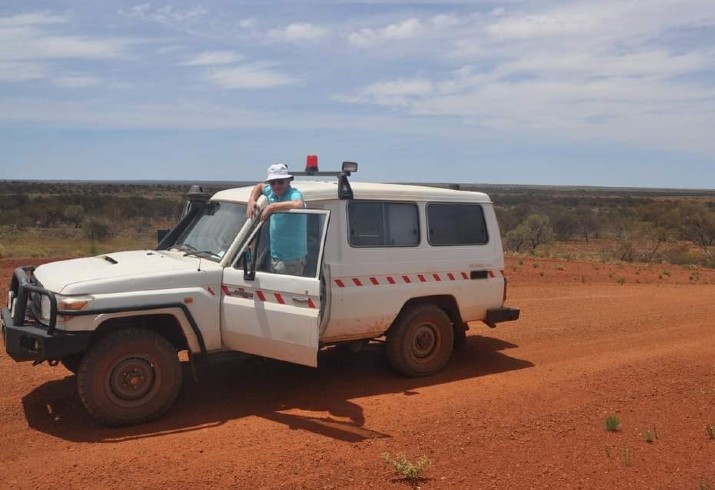 Dr Paddy Glackin on red outback road with 4WD