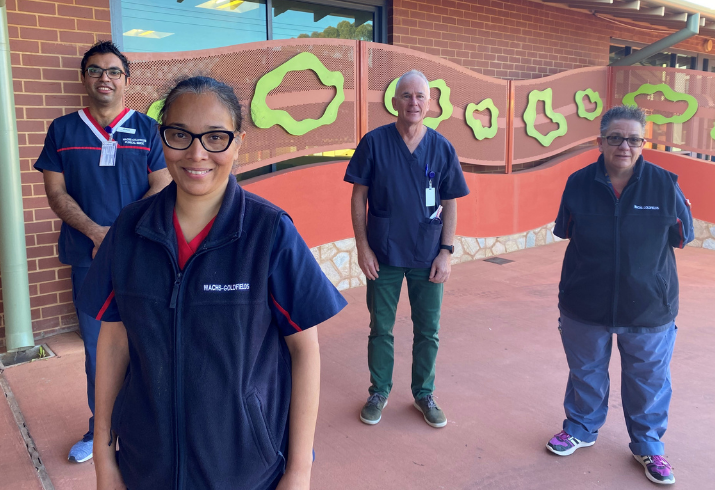 Four staff members stand outside Kalgoorlie Hospital, smiling