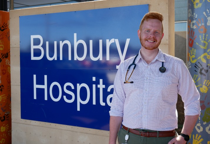 Junior doctor stands in front of Bunbury Regional Hospital welcome sign 