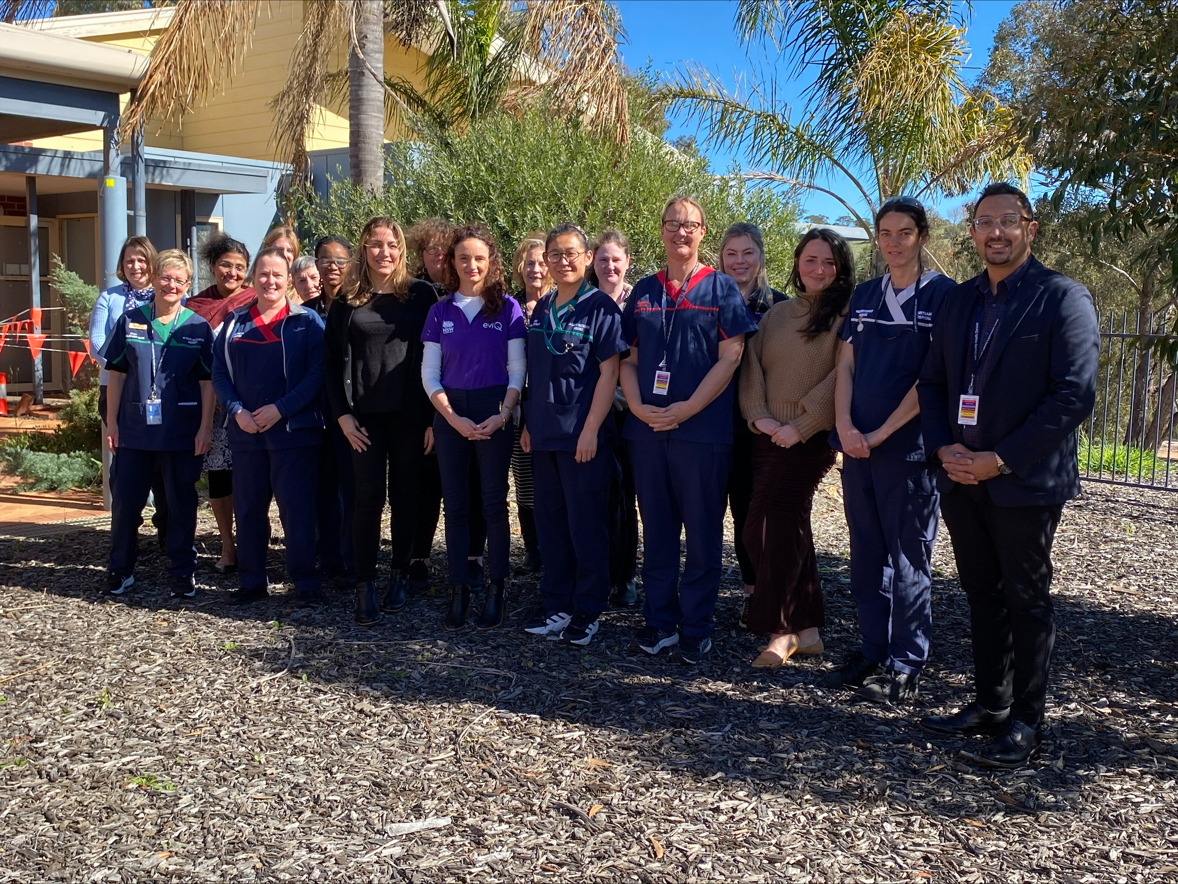 A group of nurses and clinical staff stand outside in a large group smiling