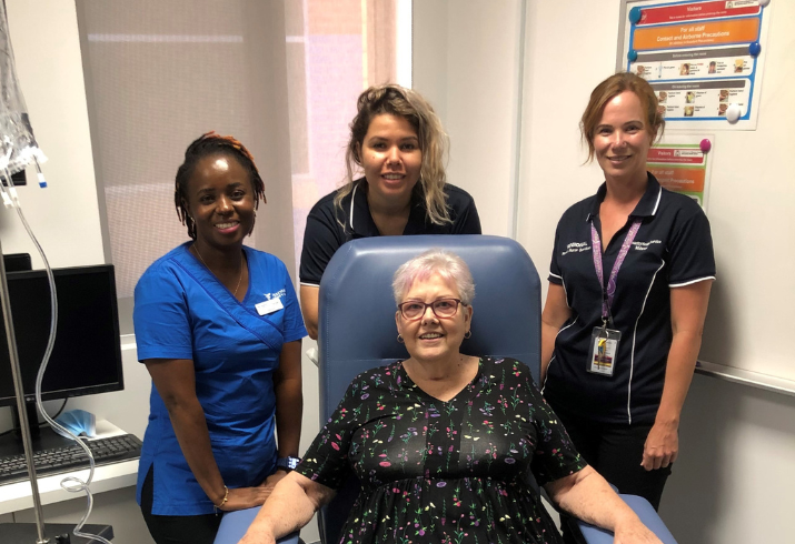 A seated patient and three nurses smile during treatment