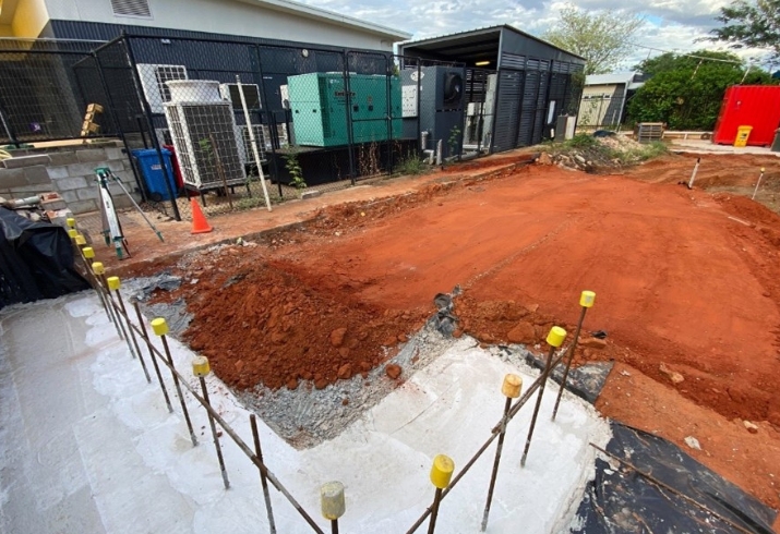 New footings and cleared red dirt form the work site for a new building next to an existing structure