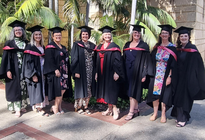 Group of graduates standing in a line in academic regalia.