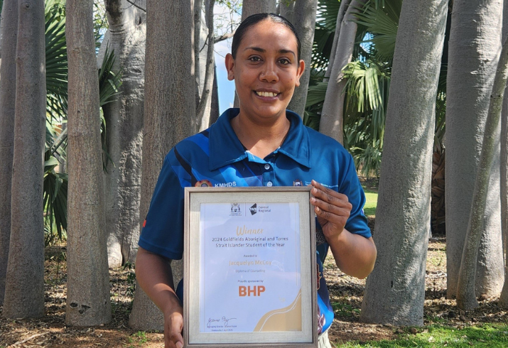 A young Aboriginal woman proudly displays a framed certificate