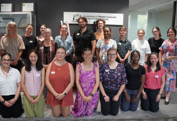 Group of people in casual dress with front line kneeling on the ground.