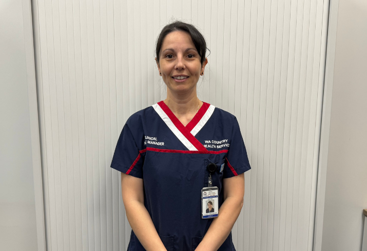 Female nurse with brown hair in navy blue srubs with red and white collar.