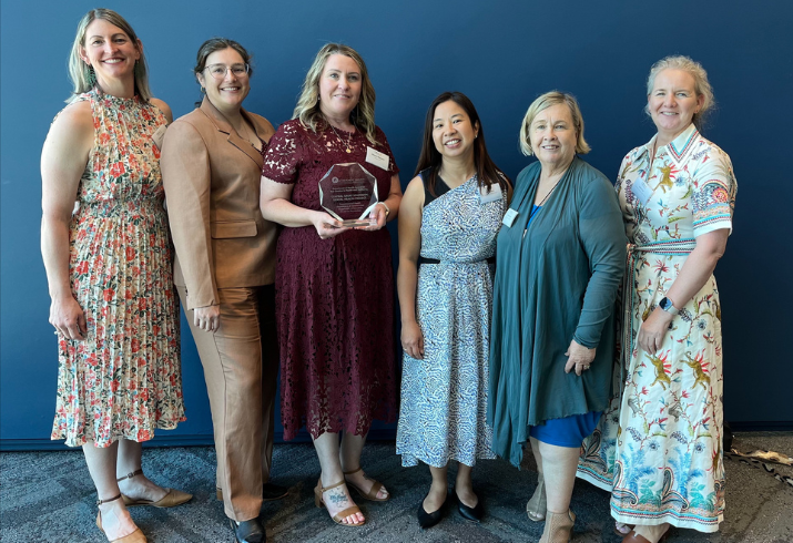 Group of six women standing in a line holding a trophey