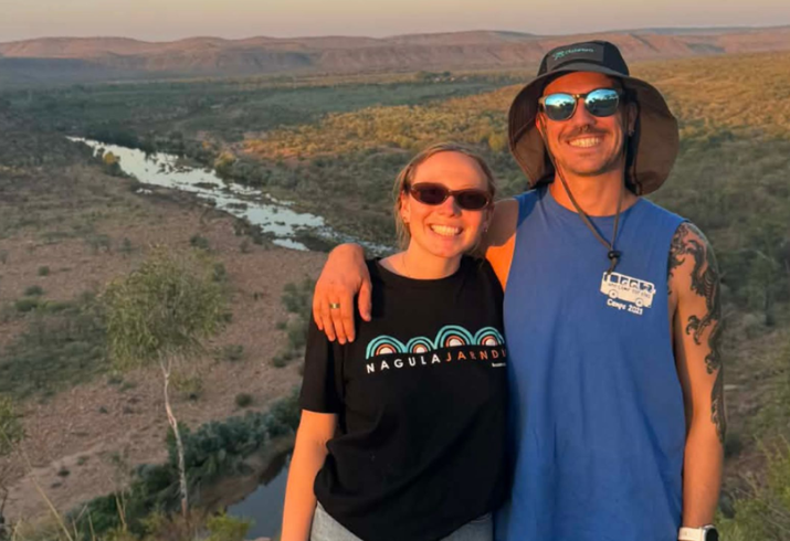 Man and woman wearing sunglasses standing in front of Kimberley landscape.