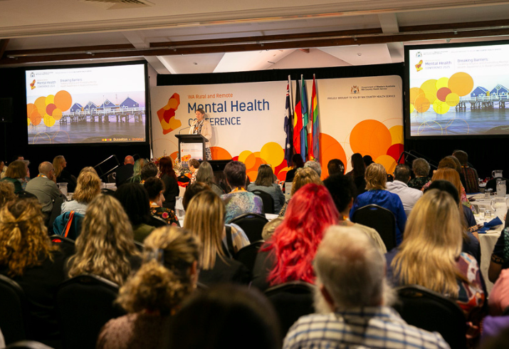 Group of people sitting facing the stage at the conference. Pictured from behind.