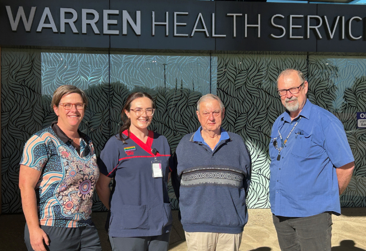 Four people standing in front of hospital sign that says 'Warren Health Service'