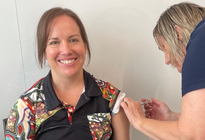 Nurse administers vaccine to seated patient 