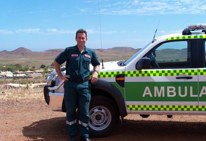 Paramedic stand in front of ambulance on country road