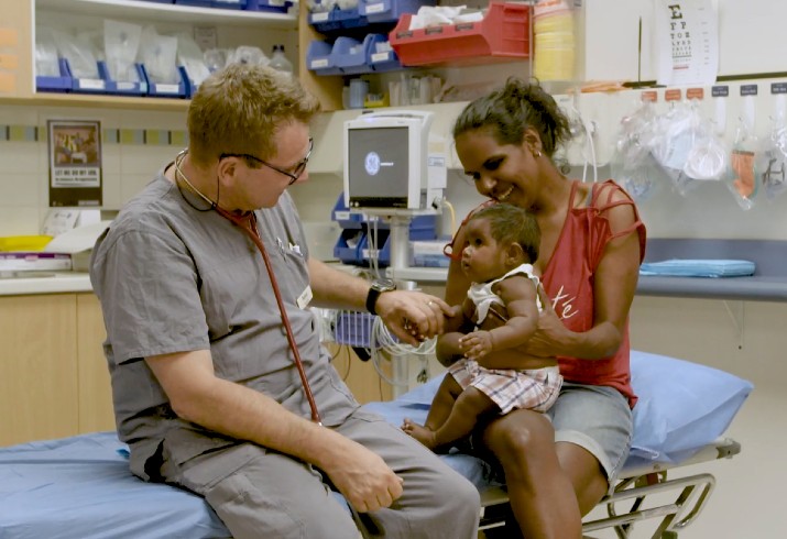 Doctor sits with mother and baby in a hospital